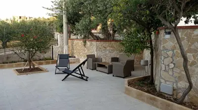 a patio with chairs and tables and a stone wall at AmarMare Bed&Breakfast in Trappeto
