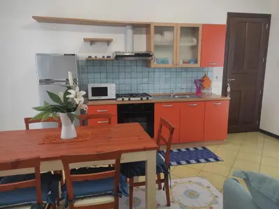 a kitchen with orange cabinets and a wooden table with chairs at Casa di Lolli in San Vito lo Capo