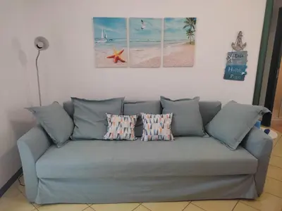 a blue couch with three pillows on it in a living room at Casa di Lolli in San Vito lo Capo