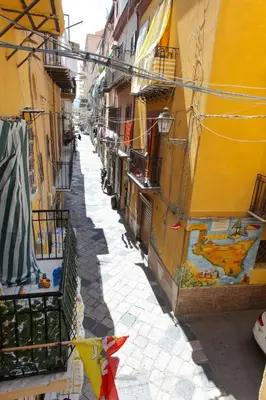 an alley with buildings and flags in a city at Apollo Apartment in Palermo