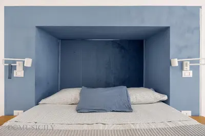 a bed with a blue headboard in a bedroom at Loggiato dei Ventimiglia By DomuSicily in Palermo