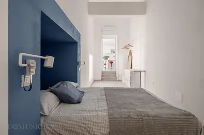a bedroom with a bed with a blue wall at Loggiato dei Ventimiglia By DomuSicily in Palermo