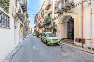 a small green car parked on a street between buildings at Casa Peppa by Wonderful Italy in Palermo