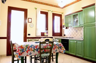 a kitchen with green cabinets and a table with chairs at Villetta Gelsomini, San Vito Lo Capo in San Vito lo Capo