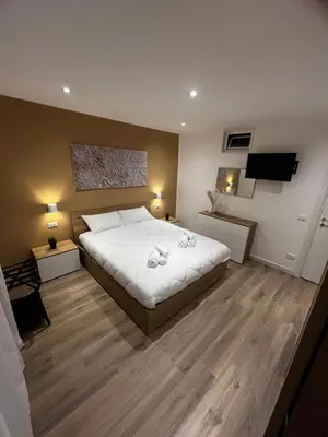 a bedroom with a large white bed and wooden floors at A CASA DI LILLY - BALLARò' - in Palermo