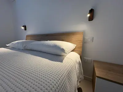 a bedroom with a white bed with a wooden headboard at Cala38 in Terrasini