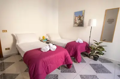 two beds in a room with pink sheets and towels at iFlat Casa Sant'Agata in Palermo