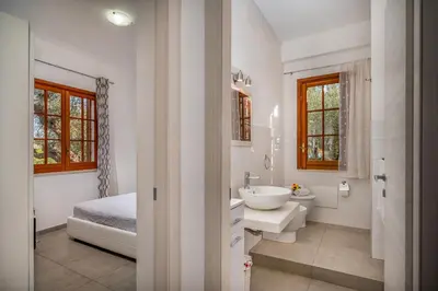a white bathroom with a bed and a sink at Villa Giummara Cala bianca in Castellammare del Golfo