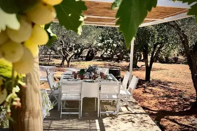a table with white chairs and a table and trees at Villa Halcón, casale con piscina tra gli ulivi, vicino al mare tra Balestrate e Alcamo in Partinico