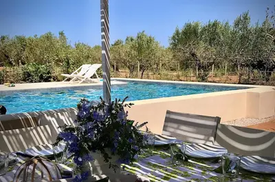a table with blue flowers on it next to a swimming pool at Villa Halcón, casale con piscina tra gli ulivi, vicino al mare tra Balestrate e Alcamo in Partinico