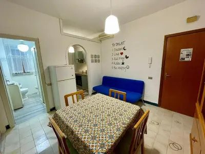 a dining room with a table and a blue chair at Delle Palme Holiday Home in Isola delle Femmine