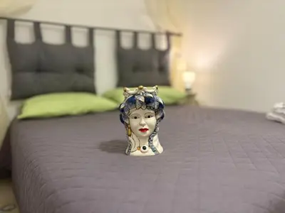 a statue of a woman with a crown on a bed at Delle Palme Holiday Home in Isola delle Femmine
