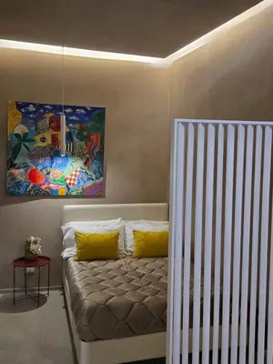 a couch with yellow pillows and a painting on the wall at Venticinque Passi - nel cuore di Palermo in Palermo