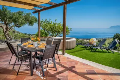 a table and chairs on a patio with a view at Vista Mare Scopello AC Jacuzzi 3 camere by Proger in Scopello