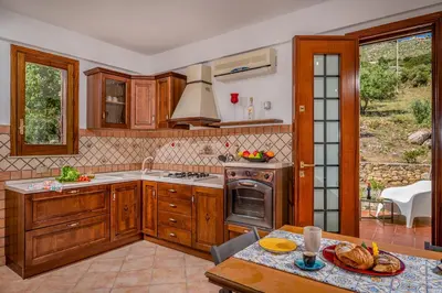 a kitchen with wooden cabinets and a table with a plate of food at Vista Mare Scopello AC Jacuzzi 3 camere by Proger in Scopello