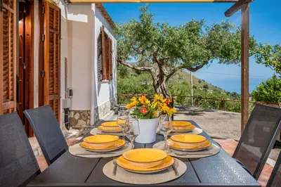 a wooden table with yellow plates and flowers on it at Vista Mare Scopello AC Jacuzzi 3 camere by Proger in Scopello