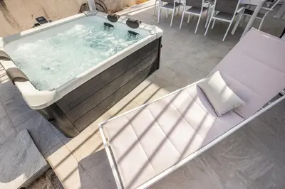 a bath tub with a chair and a table at Richgood Luxury homes - Villa Zefira sole in Altavilla Milicia