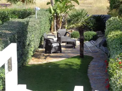 a patio with chairs and a palm tree in a yard at Villa La Chiocciola in San Vito lo Capo