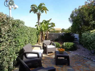 a patio with chairs and a table and palm trees at Villa La Chiocciola in San Vito lo Capo