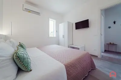 a white bedroom with a bed and a flat screen tv at Deliziosa Villa con Piscina e Jacuzzi a Scopello in Castellammare del Golfo