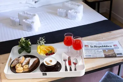 a tray with food and drinks on a bed at Suite 136 in Palermo