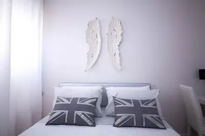 a white bedroom with a bed with two pillows at Suite 136 in Palermo