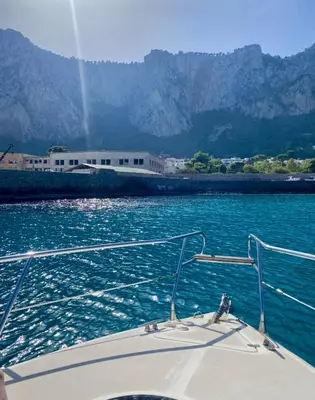 a boat in the water with mountains in the background at Palermo Boat Experience in Isola delle Femmine