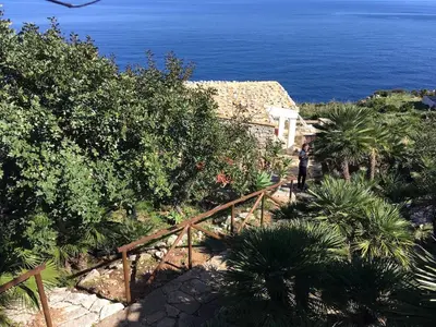 a person walking down a wooden staircase near the ocean at Chalet Le Palmette in Contrada Sauci Grande