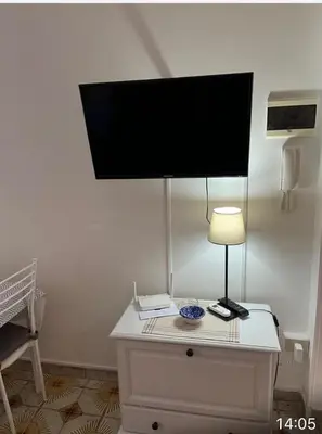 a flat screen tv on top of a dresser with a lamp at Chiaro di luna holiday in Palermo