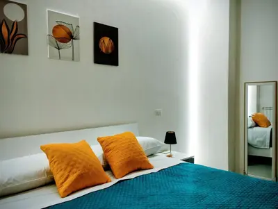a bedroom with a bed with orange pillows and a mirror at Aria di Paese in Altavilla Milicia