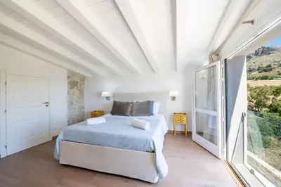 a bedroom with a bed and a large window at Villa Baja Scopello in Balata di Baida