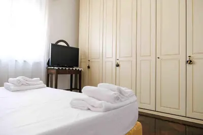 a bedroom with white towels on a bed with a television at High-end apartment in the city center in Palermo