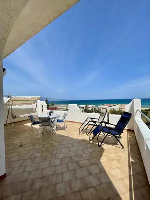 a patio with chairs and a table and the ocean at Sea view terrace house in Alcamo