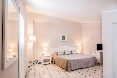 a white bedroom with a bed and a television at Hotel Tonnara Trabia in Trabia