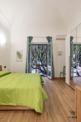 a bedroom with a green bed and a large window at Ballaria in Palermo