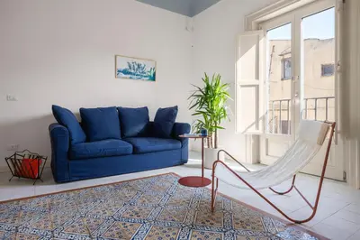 a living room with a blue couch and a chair at Casa Dara By DomuSicily in Palermo