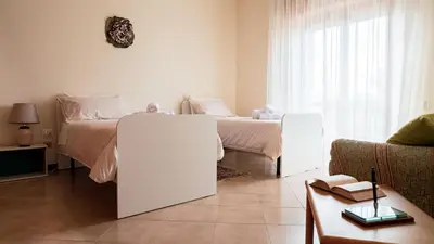 a white bedroom with two beds and a couch at Agelina square Home Gibellina in Nuova Gibellina