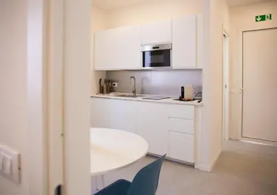 a white kitchen with a table and a microwave at Solemar Sicilia - Casa Belle in Palermo
