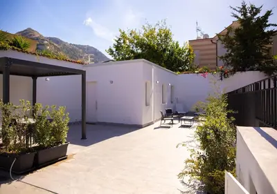 a patio with chairs and a white building at Solemar Sicilia - Casa Belle in Palermo