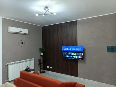 a living room with a couch and a television on a wall at La Capaciota in Capaci