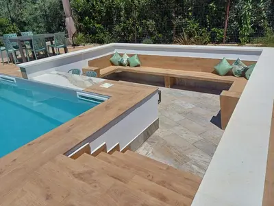 a swimming pool with wooden stairs next to a pool at Scrusciu Holiday in Terrasini