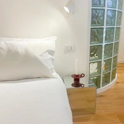 a bedroom with a white bed and a candle on a table at Palazzo Crisafulli Suite in Palermo