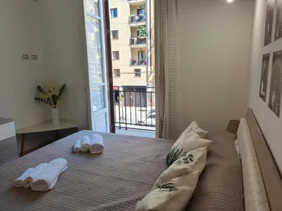 a bedroom with a bed with slippers and a balcony at Central Station Apartaments Casa Vacanze in Palermo