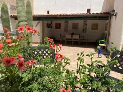 a garden with red flowers in front of a house at Rifugio Giudeo in Balestrate