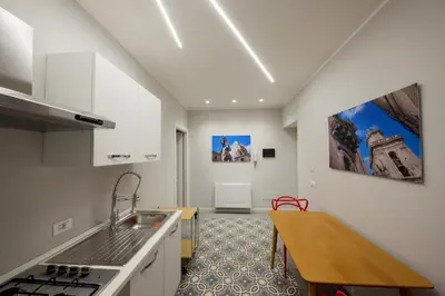 a kitchen with white cabinets and a wooden table at Romantic Suite in Palermo