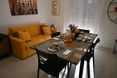 a dining room table with food and a yellow couch at Alla Metro in Capaci