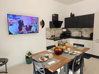 a kitchen with a dining table and a tv on the wall at Alla Metro in Capaci