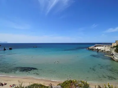 a beach with people swimming in the water at Apartment Wohnung dei Mori in Terrasini by Interhome in Terrasini