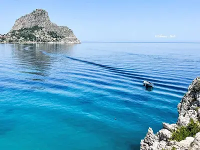 a boat in the water next to a small island at Apartment Sea Living Sicilia Apartment by Interhome in Santa Flavia