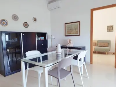 a dining room with a glass table and white chairs at Alessandra in Alcamo